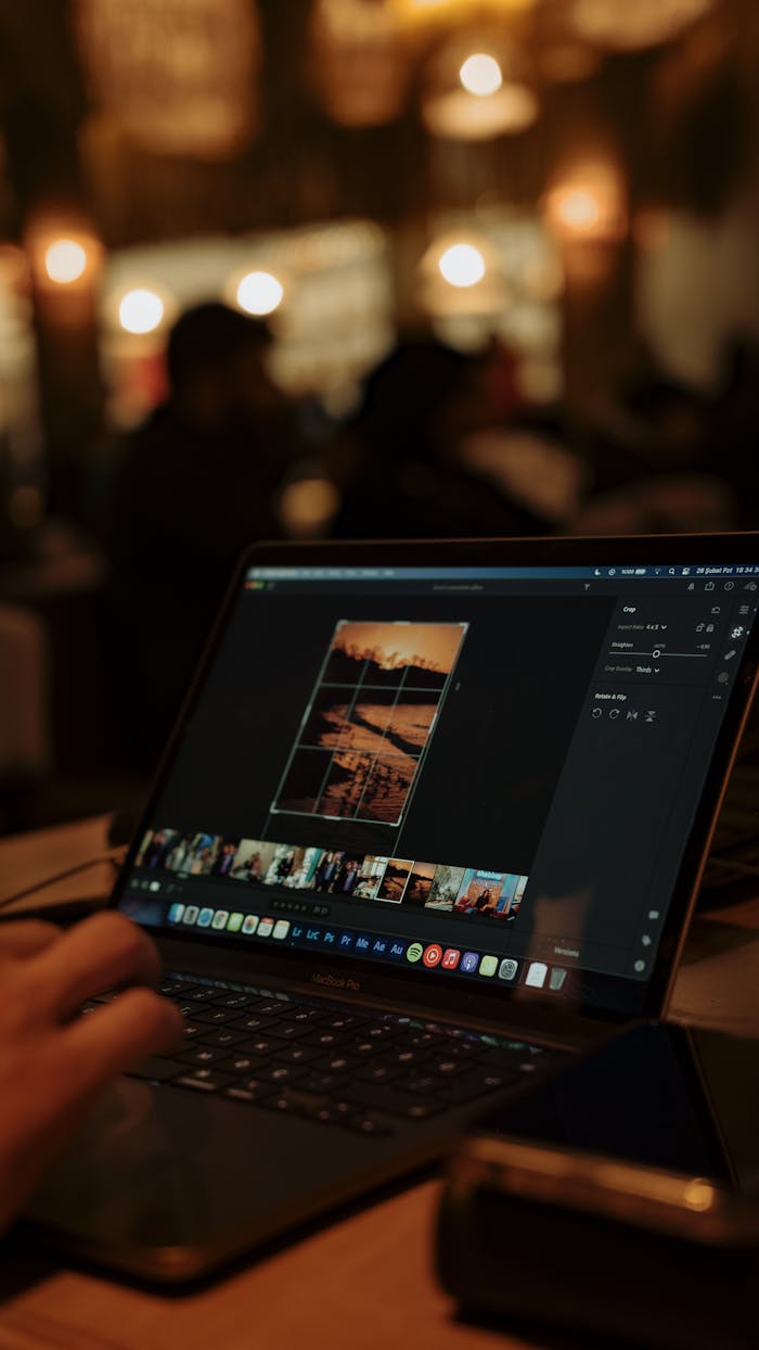 gallery-5 Person editing photos on a laptop in a dimly lit cafe, creating a cozy ambiance.